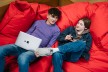 Two teenagers on a beanbag with notebook