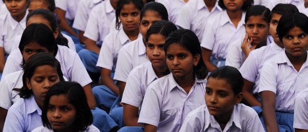 Schoolchildren in uniform, sitting in file on the ground