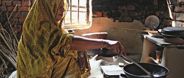 Eine Frau kocht in einer einfachen Hütte auf einem Biogasherd