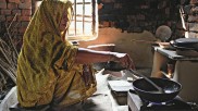 Eine Frau kocht in einer einfachen Hütte auf einem Biogasherd
