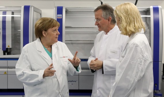 Bei ihrem Besuch der Biotech-Firma Centogene lassen sich Bundeskanzlerin Angela Merkel (CDU, l) und Manuela Schwesig (SPD), Ministerpräsidentin von Mecklenburg-Vorpommern, im Labor für DNA-Sequenzierung von Arndt Rolfs