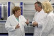 Bei ihrem Besuch der Biotech-Firma Centogene lassen sich Bundeskanzlerin Angela Merkel (CDU, l) und Manuela Schwesig (SPD), Ministerpräsidentin von Mecklenburg-Vorpommern, im Labor für DNA-Sequenzierung von Arndt Rolfs