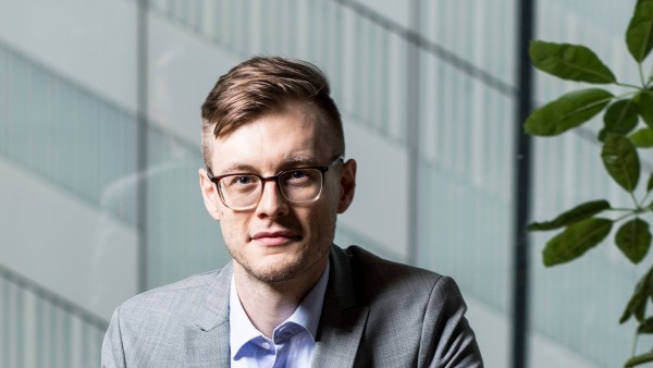 Porträt von Yannik Schreckensberger. Der 32jährige sitzt auf einem Stuhl in seinem Büro.