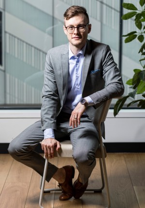 Portrait of Yannik Schreckensberger. The 32-year-old sits on a chair in his office.