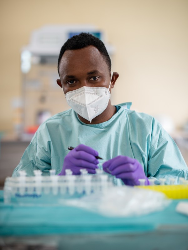 Ein Labormitarbeiter trägt Mundschutz und beschriftet eine Phiole