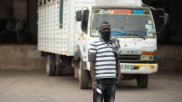 A Kenyan trucker stands in front of his truck