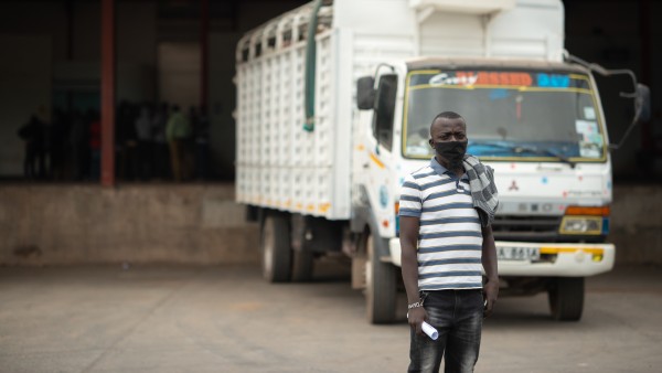 A Kenyan trucker stands in front of his truck