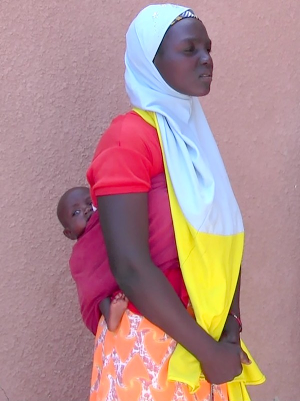 A mother carrying a baby on her back