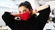 Demonstration of a red protective mask manufactured by Stitch by Stitch