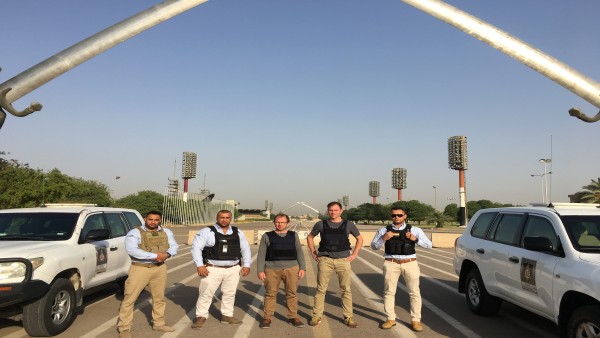Five men stand in front of the monument of crossed swords, Iraq.
