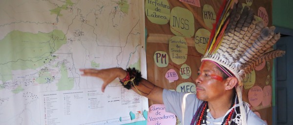 Mitglied eines bedrohnten Stammes zeigt auf einer Landkarte die betroffene Region