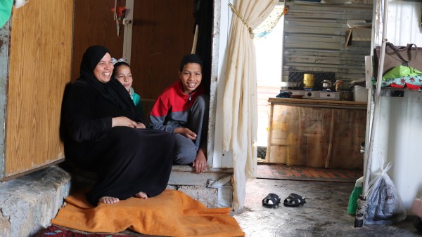 A woman and two children sit in an accommodation for refugees in Za'atari