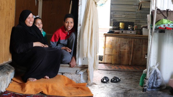 A woman and two children sit in an accommodation for refugees in Za'atari