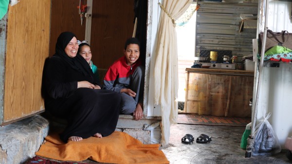 Frau sitzt mit zwei Kindern in einer Flüchlingsunterkunft in Za'atari
