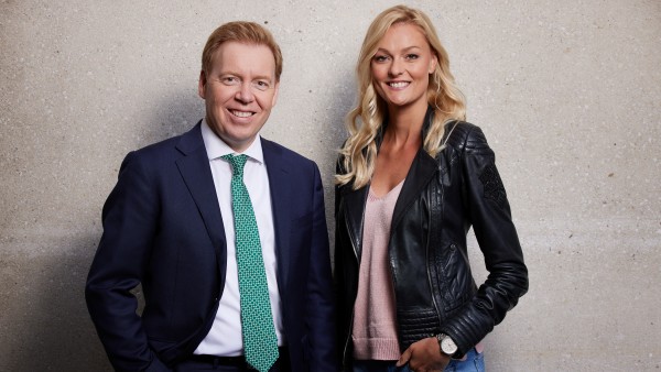 A woman and a man stand smiling in front of a wall for a portrait