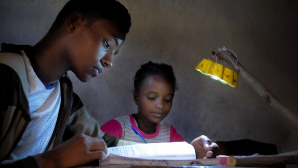 School children doing their homework, illuminated by a Little Sun solar lamp