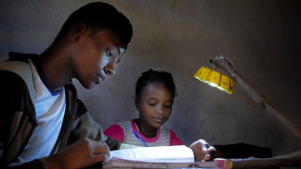 School children doing their homework, illuminated by a Little Sun solar lamp