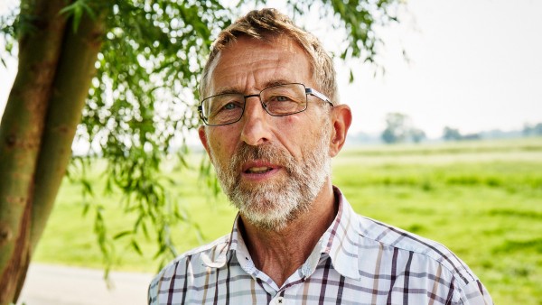 Der Bürgermeister von Nortorf Manfred Boll steht vor einem grünen Feld. 