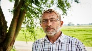 Der Bürgermeister von Nortorf Manfred Boll steht vor einem grünen Feld. 