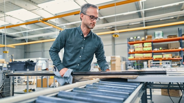 Mitarbeiter begutachtet ein Rohr in der Produktionshalle