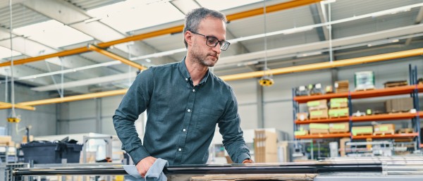 Mitarbeiter begutachtet ein Rohr in der Produktionshalle