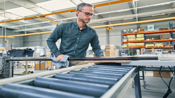 Mitarbeiter begutachtet ein Rohr in der Produktionshalle