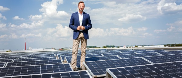 Georg Schmiedel standing between solar panels