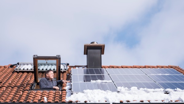 Ein Mann schaut aus einer Dachluke auf seine Photovoltaik-Module.