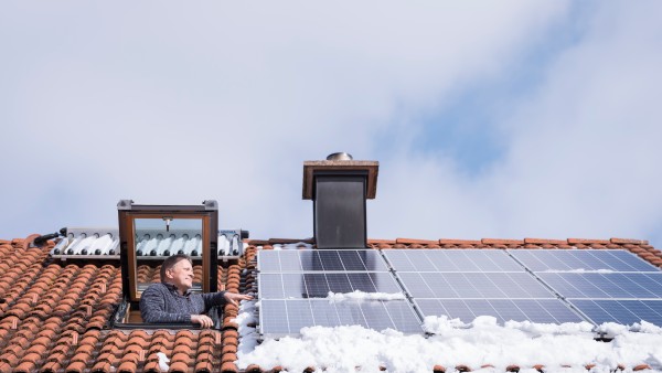 Ein Mann schaut aus einer Dachluke auf seine Photovoltaik-Module.