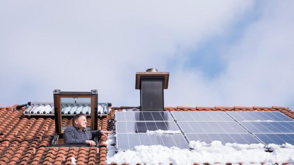 A man looks out of his rooftop window onto his photovoltaic modules.