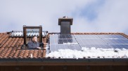 Ein Mann schaut aus einer Dachluke auf seine Photovoltaik-Module.