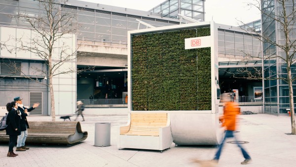 Passanten vor einem moosbewachsenen CityTree am Bahnhof