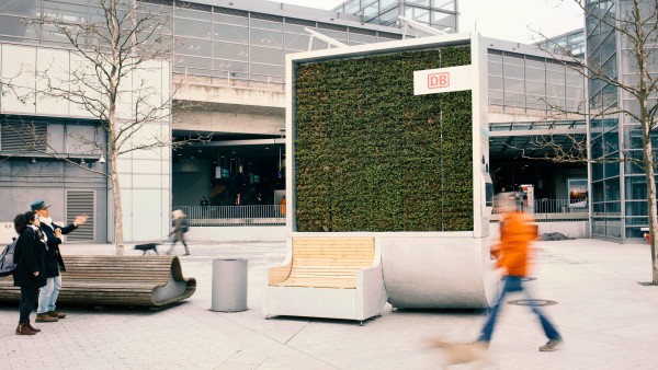 Passanten vor einem moosbewachsenen CityTree am Bahnhof