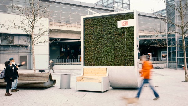 Passanten vor einem moosbewachsenen CityTree am Bahnhof