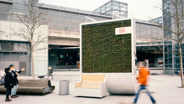 Passanten vor einem moosbewachsenen CityTree am Bahnhof