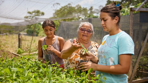 A farmer works with her granddaughters in the community's plant garden