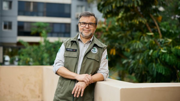Portrait of Mauro Pires, Brazilian environmental expert and director of ICMBio (Instituto Chico Mendes de Conservação da Biodiversidade), leaning against a wall ledge in a garden.