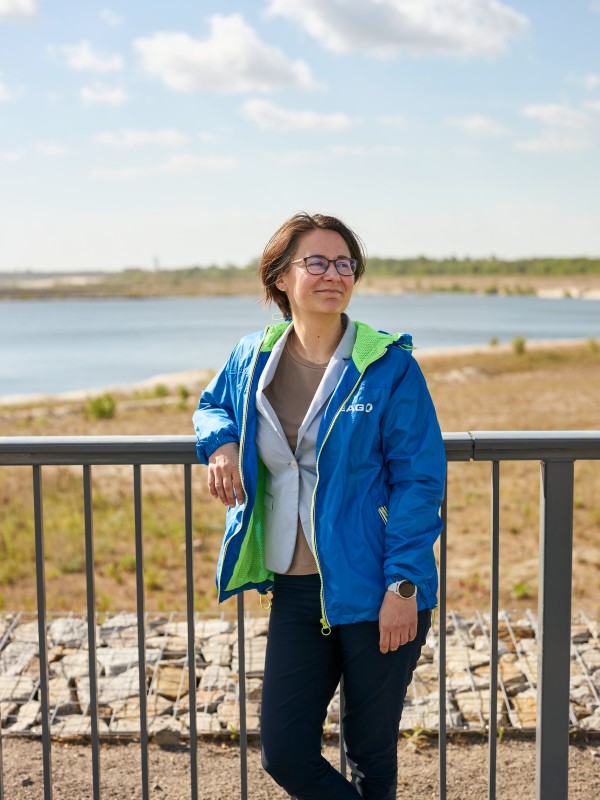 Frau vor Geländer mit See im Hintergrund