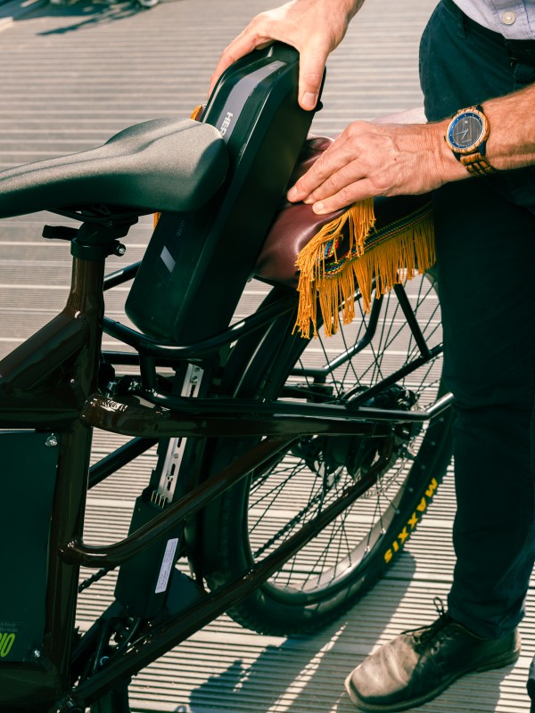 Two hands push the battery of an e-bike into its holder.