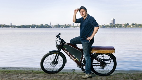 Schauspieler Bjarne Mädel auf dem African E-Bike an der Alster.