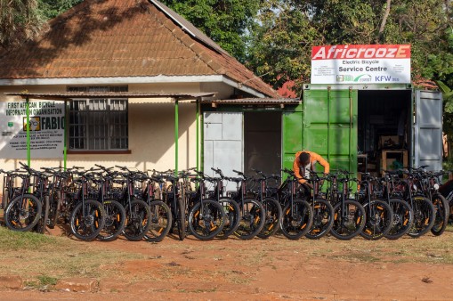 There are many e-bikes in front of a house and container
