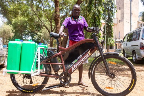 Eine Frau hält ein E-Bike mit daran befestigten Kanistern.