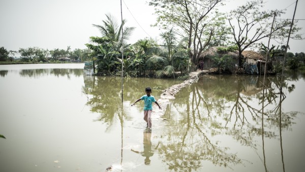 A little boy is crossing flooded grounds in Bangladesh