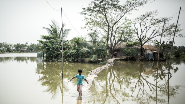 A little boy is crossing flooded grounds in Bangladesh