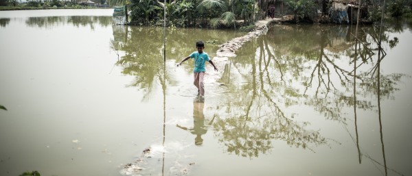 A little boy is crossing flooded grounds in Bangladesh