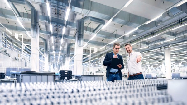 Zwei junge Männer begutachten in einer Produktionshalle die Produkte