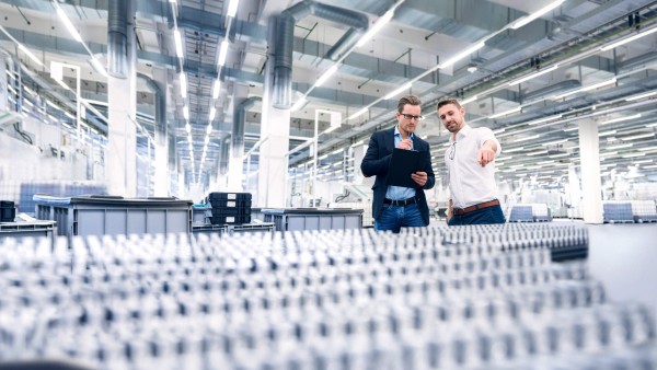 Two young men examine the products in a production hall