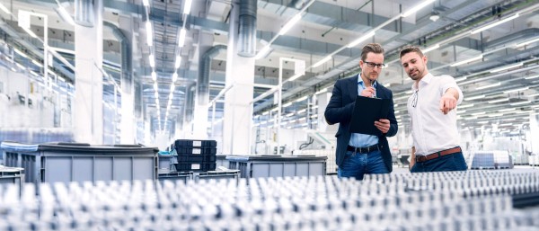 Zwei junge Männer begutachten in einer Produktionshalle die Produkte