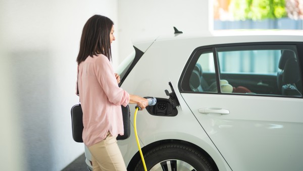 Eine Frau steckt ein Ladekabel in ein E-Auto