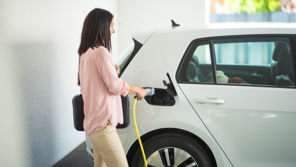 Eine Frau steckt ein Ladekabel in ein E-Auto